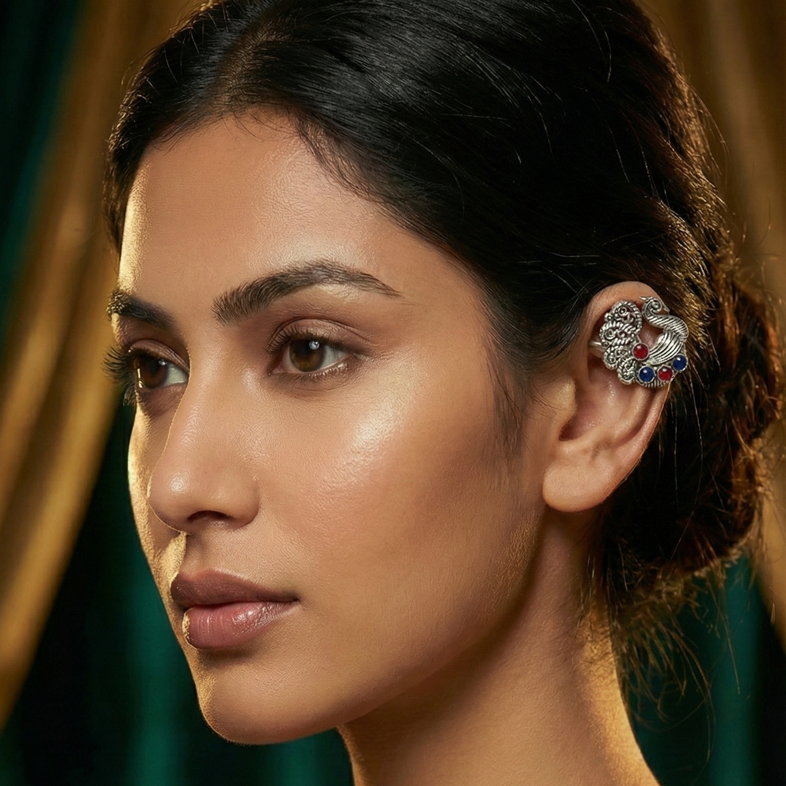 Woman wearing a decorative earring with a green curtain background