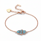 Rose gold bracelet with a blue and green evil eye charm on a white background