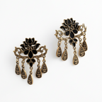 Pair of ornate earrings with black and gold designs on a white background