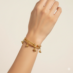 Gold bracelet with charms on a hand against a beige background