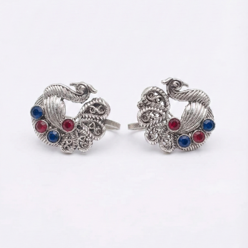 Pair of silver earrings with red and blue gemstones on a white background