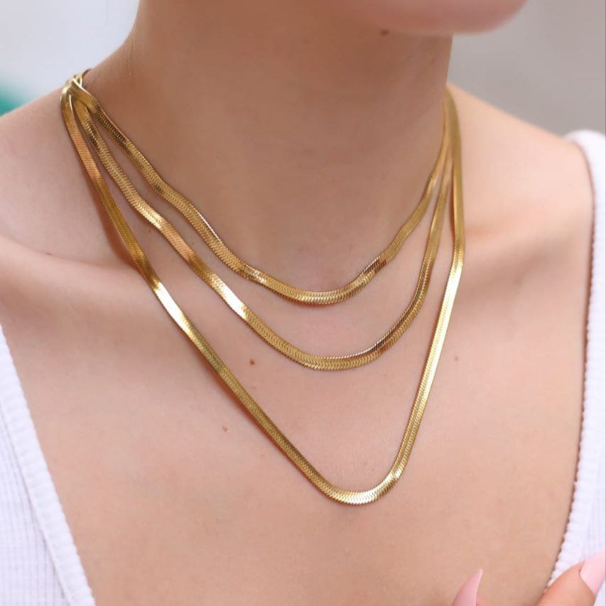 Gold necklace on a person wearing a white top