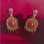 Antique gold and red dangle earrings with tribal-inspired patterns, intricate detailing, and beaded fringes, perfect for boho-chic and festive wear.